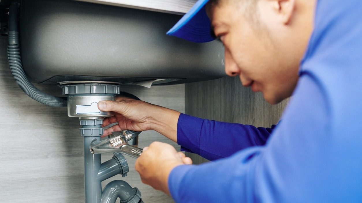 Plumber fixing leaking pipes in a London home